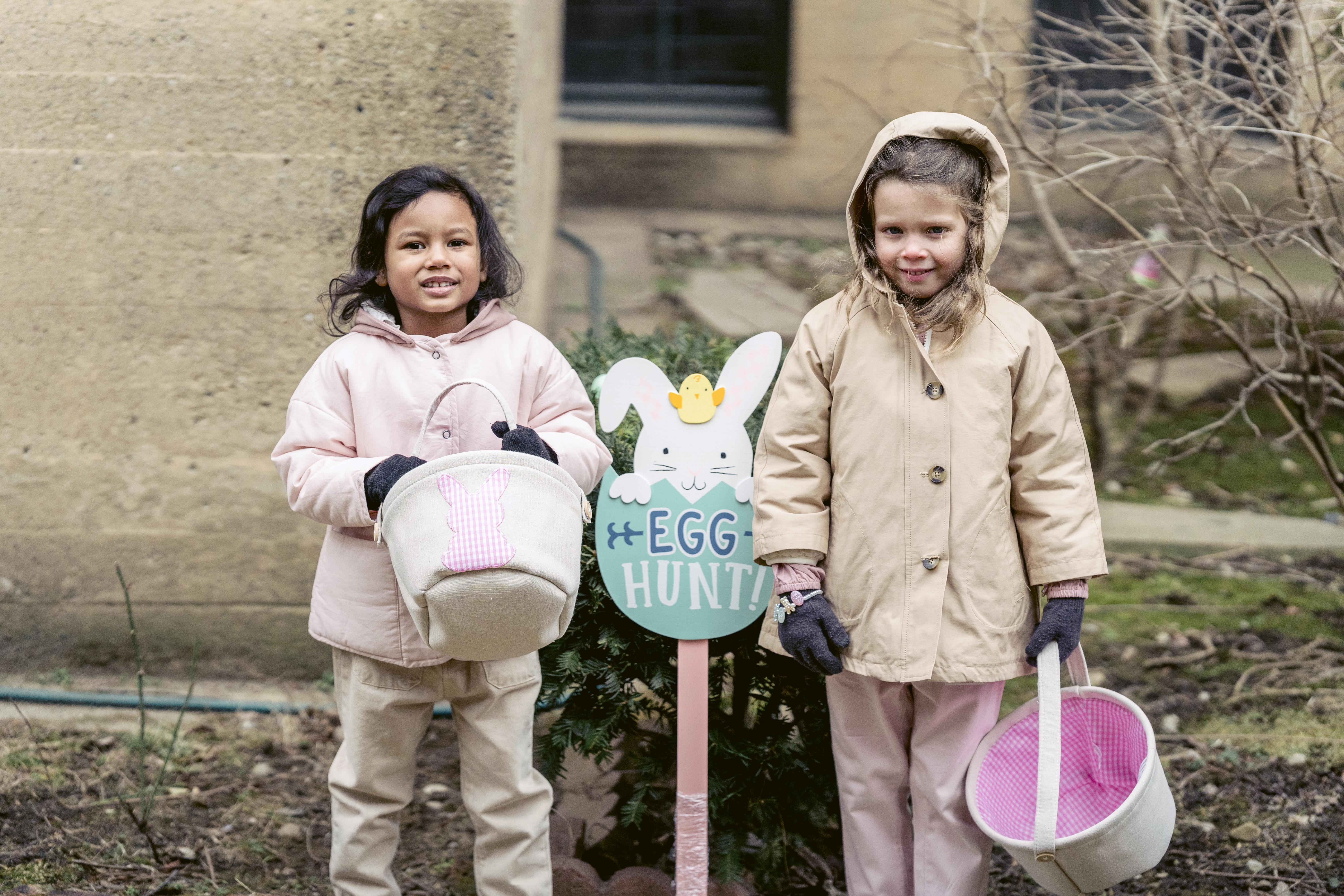 Adorable diverse girls in warm coats hunting eggs