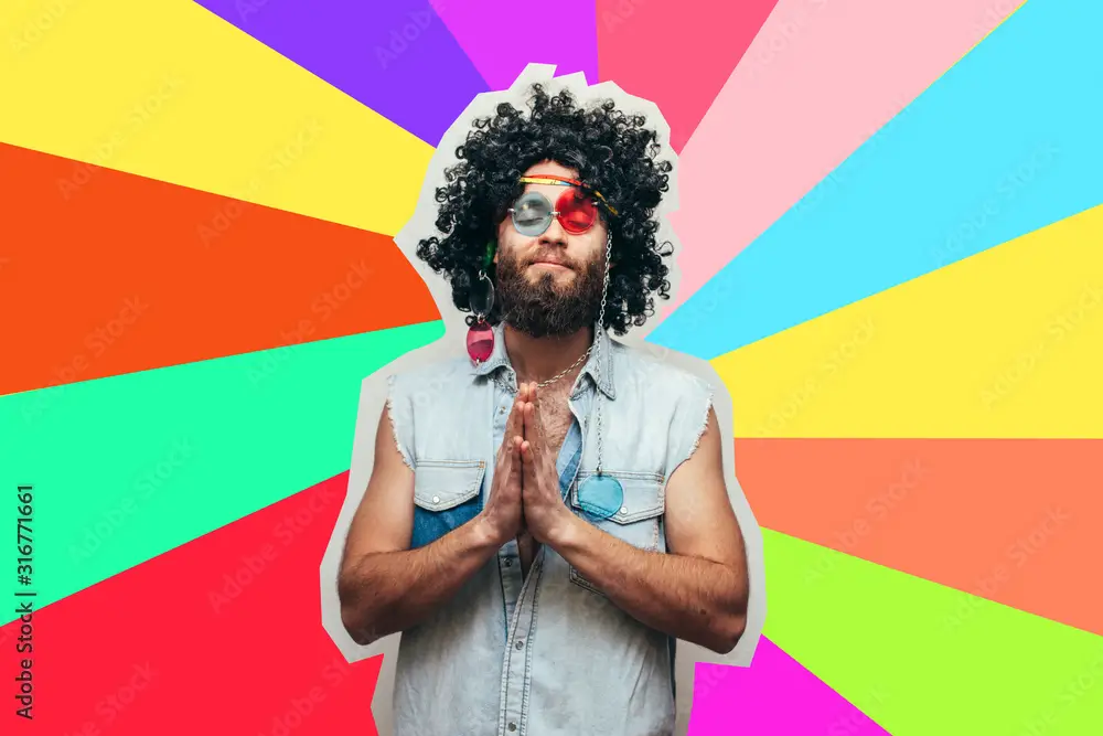Friendly bearded young male hippie with curly hair in stylish sunglasses isolated on colorful background